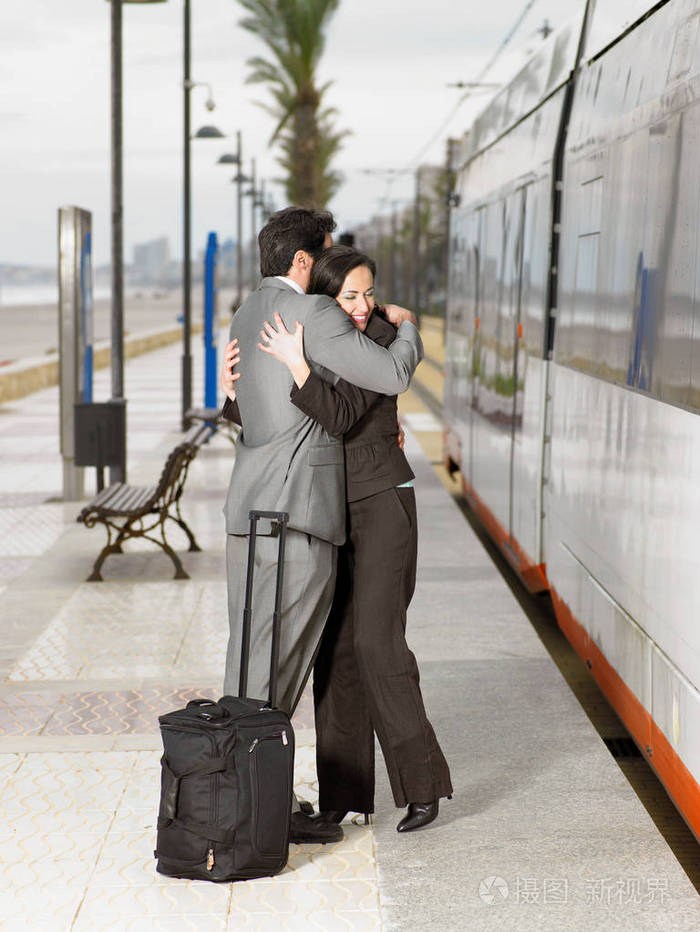 穿西装的情侣在电车站拥抱