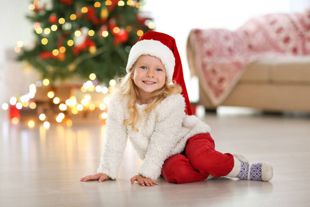 戴着圣诞帽的可爱小女孩坐在家里的地板上
