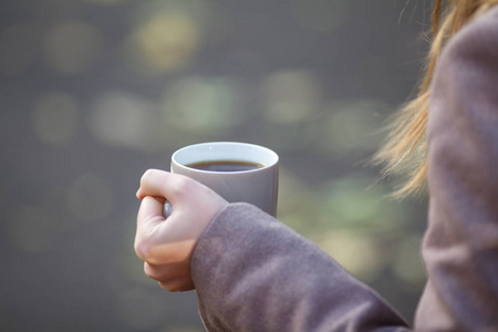 秋天的公园中的杯持有咖啡或茶