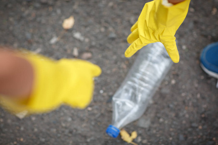 s hands in yellow latex gloves. Children picking up the plastic 