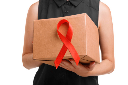 关闭一个浅棕色的纸箱，红色丝带在一个支持的女性手中隔离在白色背景上。 非法药物有助于疾病和酒后驾驶预防。 世界艾滋病日。