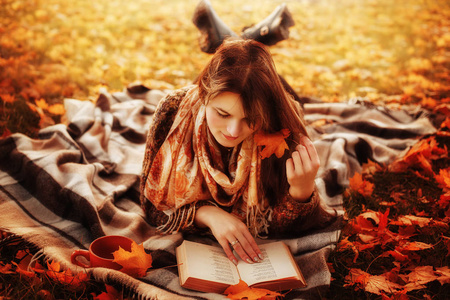 美丽的年轻黑妞，坐在一个堕落的秋天叶子在