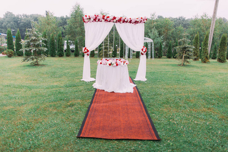 水平视图的婚礼拱门和餐桌上点缀着鲜花和挂在草地上的豆子