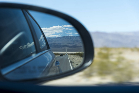 汽车在高速公路上行驶，沿着令人惊叹的山景，从侧镜看到。