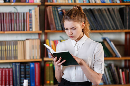 一个年轻的女孩，在图书馆读书的肖像