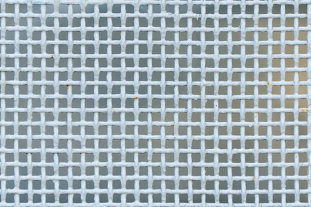 光蓝生锈栅栏的金属丝网，方形细胞，一个模糊的背景。特写镜头。前视图