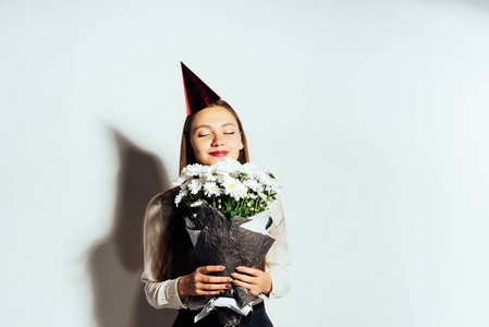 在节日帽女孩闻一束鲜花在她的手