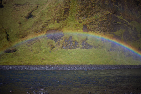 背景下的岩石，山脚下斯科加瀑布瀑布，冰岛的彩虹