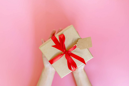 顶视图的手女人拿着棕色的礼物盒上粉红色的新年