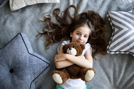 小女孩在床上玩玩具熊