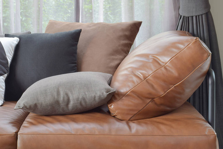 带不同颜色和大小枕头的棕褐色真皮沙发床