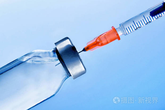 小瓶与穿刺注射器闭上蓝色的背景