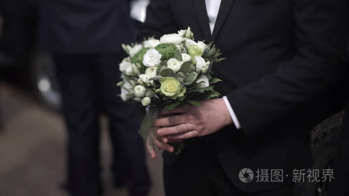 新郎在一套西装,拿着一束鲜花.婚礼