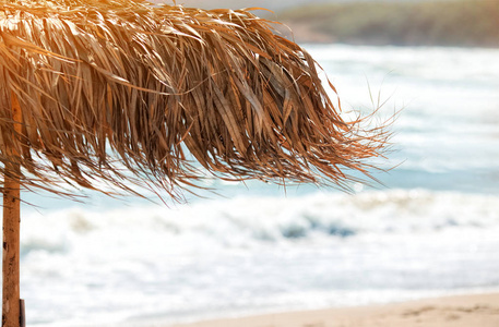 沙滩上的稻草伞。在热带沙滩上的稻草伞, 有选择的焦点, 海模糊的背景。夏季背景