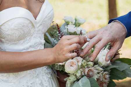 新郎在新娘的手上放置戒指。照片特写