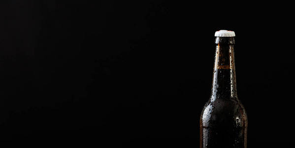黑色背景下的啤酒瓶特写图片