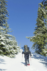 冬天在山上徒步旅行。一个男人爬上山顶