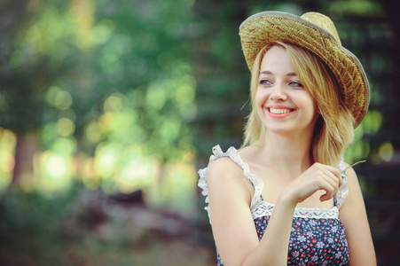 一个健康的女人美丽夏日模特女孩带着鲜艳的花朵快乐的森林。风格休闲。一个漂亮的白女人戴着草帽一个微笑和神秘的漂亮的脸。横幅和广告的