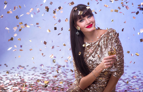 美丽的快乐的女人与玻璃香槟在庆祝聚会与五彩纸屑落在她的任何地方。生日或新年前夕庆祝概念