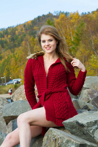 年轻女孩在红色开衫反对秋天叶子的背景