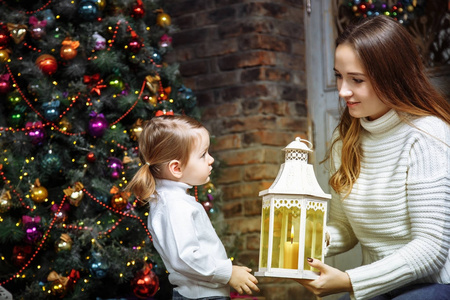 圣诞节前夕, 一个年轻的母亲和她的女儿在一个温馨的房间里点燃蜡烛