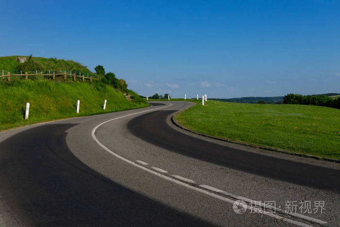 空旷的沥青弯弯曲曲的道路穿过绿色的田野.