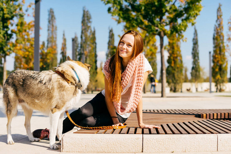 微笑可爱的 redhaired 女孩坐在公园在一个阳光明媚的一天, 她的大狗