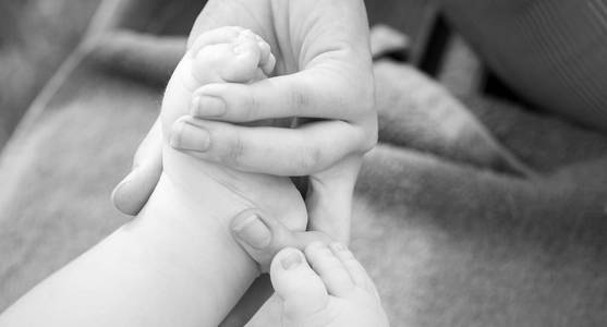 母亲手里的婴儿脚全景。幸福家庭和家庭支持的概念, 黑白照片