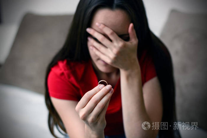 照片 哭着悲伤的年轻女人,手里拿着订婚戒指. 离婚后的抑郁.