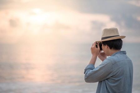 在热带海滩的日落拍照的年轻人旅行者