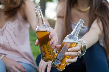 接近两个年轻的女人品尝啤酒瓶乐趣。