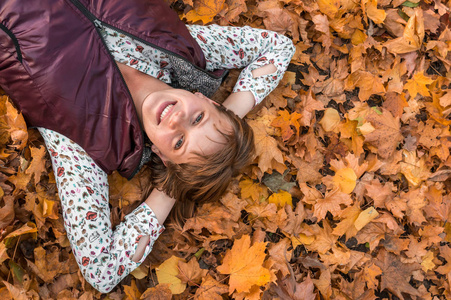 有魅力的女人躺在公园的秋叶上