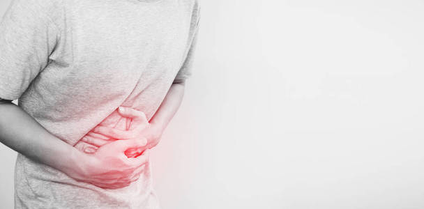 一个男人手捂腹部，红色突出显示的肚子痛的概念和其他胃病，与副本空间的白色背景上