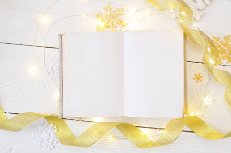 样机圣诞或新年框架组成。木制背景下的书和金色圣诞装饰品的样机。假日和庆祝概念为明信片或邀请。顶部视图