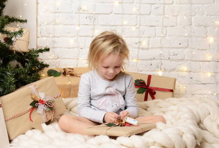 年轻的女孩坐在梦幻般的新年礼物附近的圣诞圣诞树
