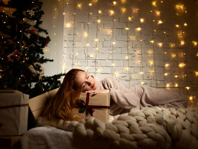 年轻女子躺在梦幻的新年礼物附近的圣诞圣诞树