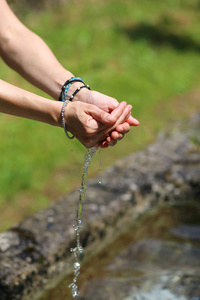 从喷泉收集淡水的女孩的手