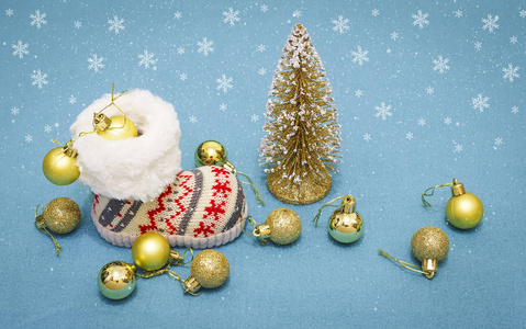圣诞假期的概念。圣诞靴与金色的球和圣诞树在蓝色的背景下飘落的雪花。冬天庆祝概念