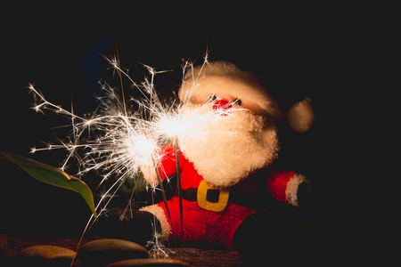 圣诞老人玩偶在圣诞节天在黑暗的背景与火花