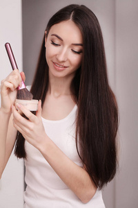 一位年轻女子用刷子在脸上涂上液体粉底