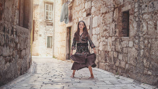 可爱的年轻女孩走在老城。中世纪城市的好女孩