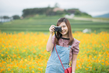 亚洲女孩拍照绽放黄色花朵, 旅游理念