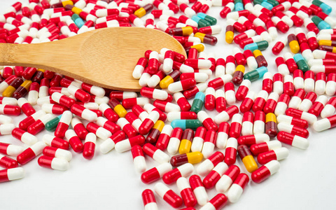 五颜六色的抗生素胶囊丸和木勺白色背景。耐药性概念。合理和全球医疗保健概念的抗生素用药