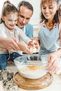 幸福的家庭在厨房的碗里劈鸡蛋