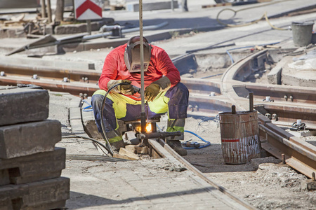 工人与防护面具焊接电车轨道在城市