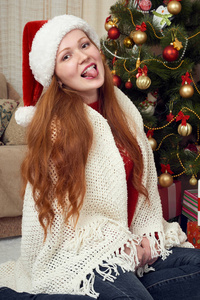 美丽的红头发女孩在圣诞节装饰的肖像。家庭内部与冷杉树和礼物。新年前夕和寒假概念