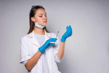 严重的年轻女子医生在白色的医疗睡衣持有注射器在手