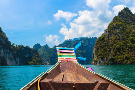 泰国长虹兰湖风景区景观。部分传统泰国尾船的前景。绿色的山和戏剧性的天空背景。选择性的关注船。泰国旅游