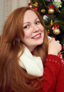 美丽的红头发女孩在圣诞节装饰的肖像。家庭内部与冷杉树和礼物。新年前夕和寒假概念