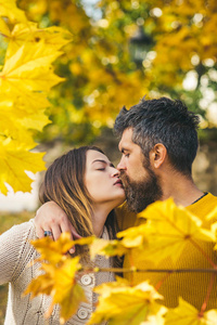 秋天愉快的夫妇在爱与黄色树叶子